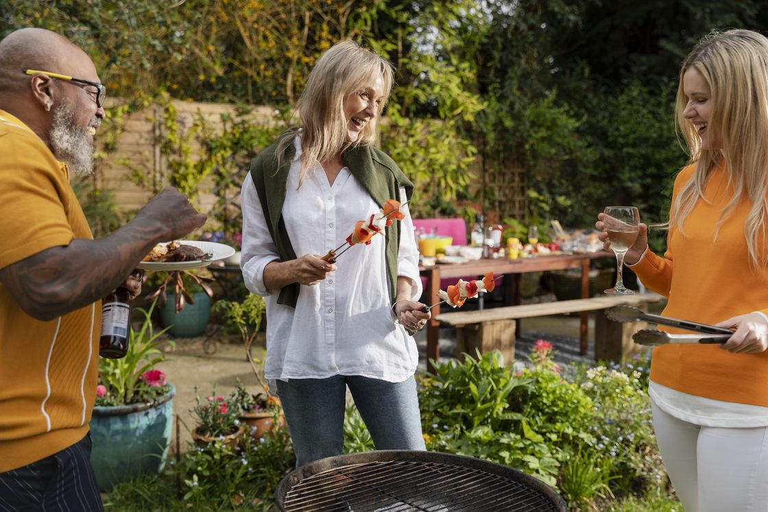 Neighbors share grilled skewers and laughter at a backyard cookout.